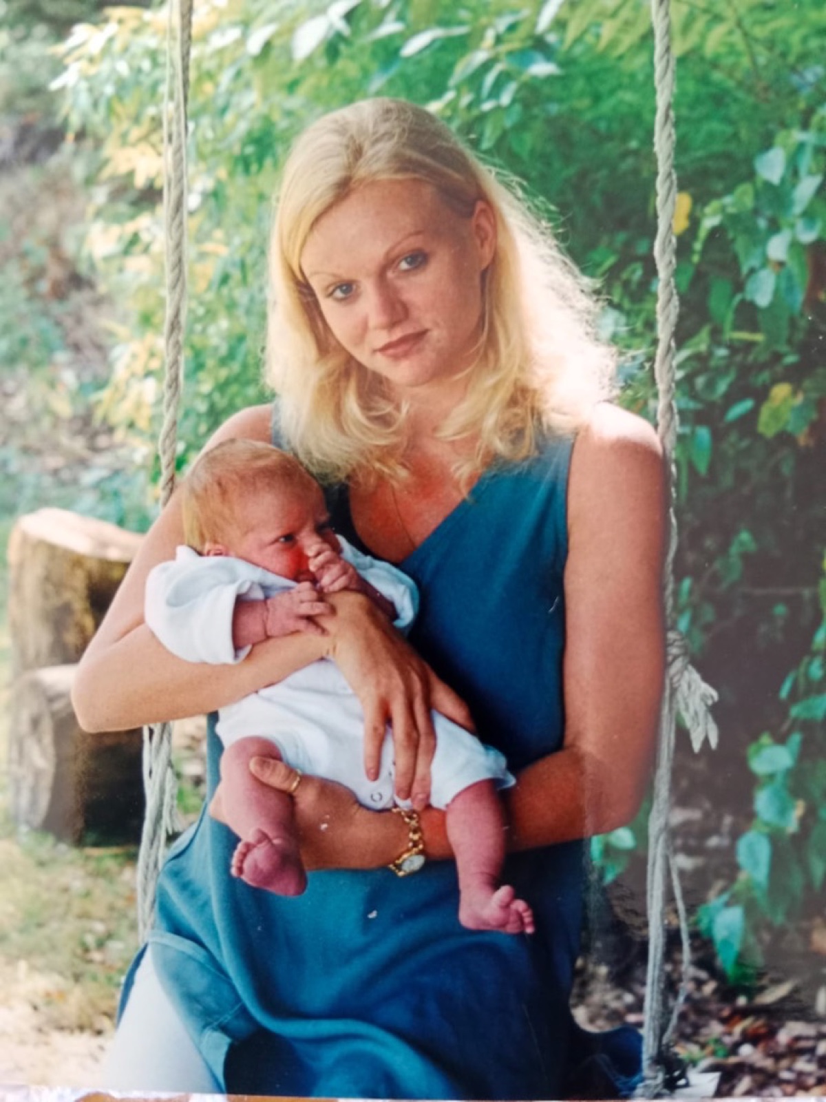 Alysha holding her newborn son on a garden swing